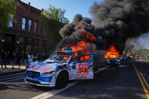 FILE - Multiple Waymo taxis burn near the Metropolitan Detention Center of downtown Los Angeles, Sunday, June 8, 2025, following last night's immigration raid protest. (AP Photo/Eric Thayer, File)